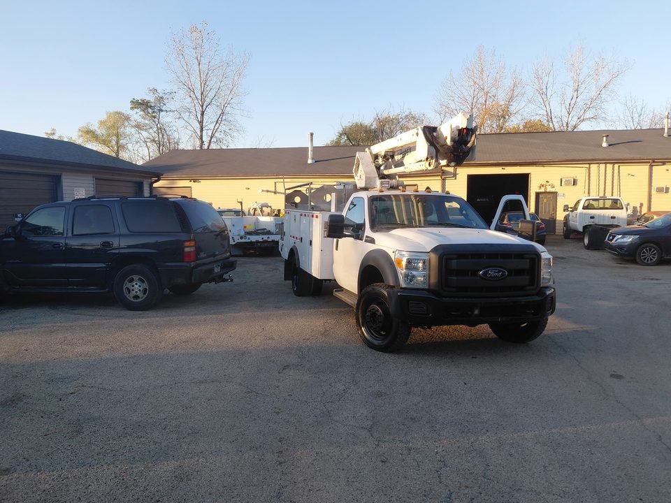 Finished F-450 bucket truck seen from the front, with the boom stowed above the cab