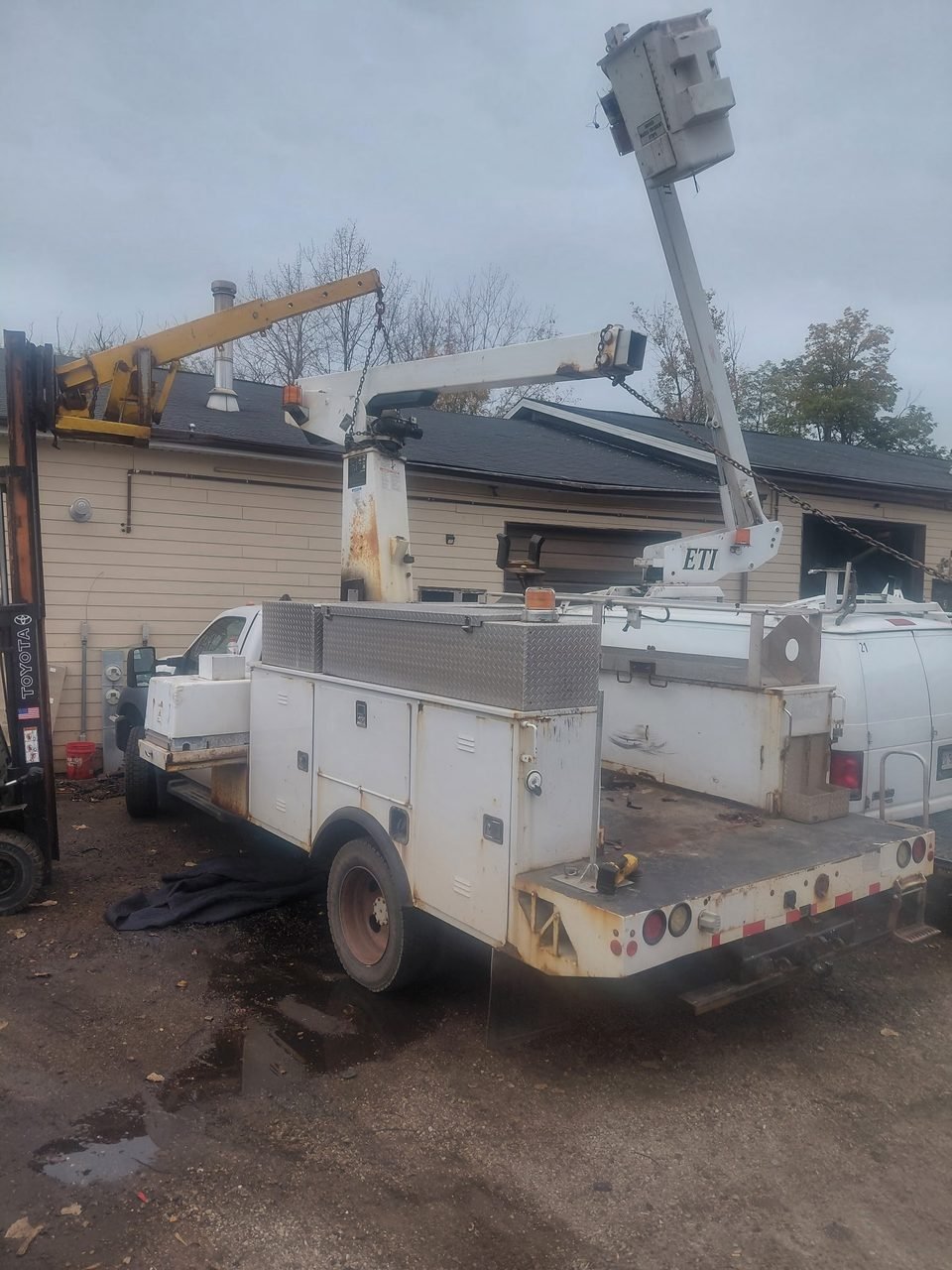 Rear view of the retired F-450 bucket truck before work, showing the worn utility body and rear bumper