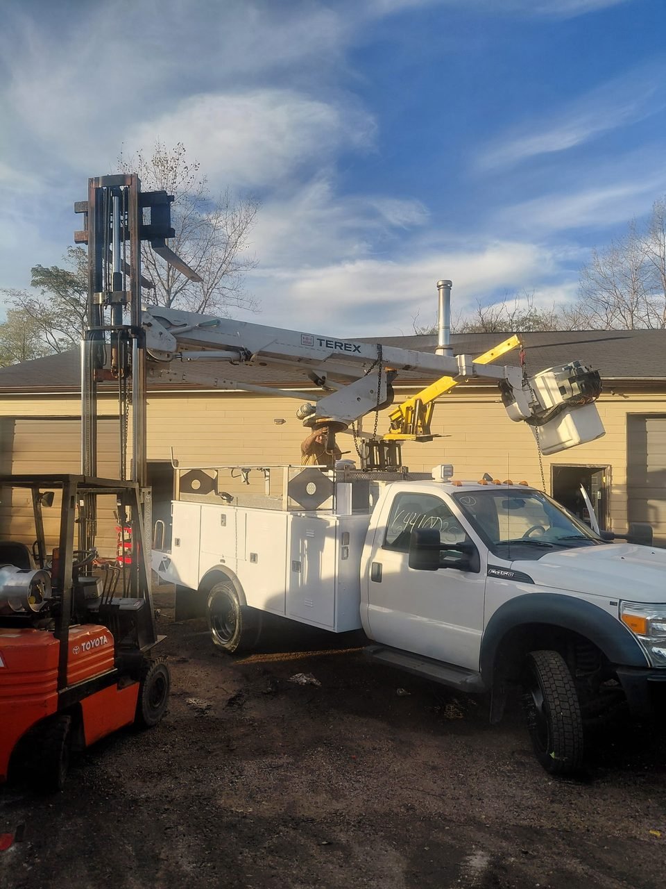 F-450 bucket truck beside a forklift with its aerial equipment raised during the project